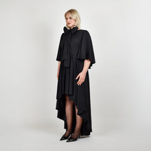 Load image into Gallery viewer, Side view of the Femponiq Bow Tie Neck Cape Sleeve Maxi Dress in Black showcasing its elegant bow tie neckline, flowing cape sleeves, and floor-length silhouette.