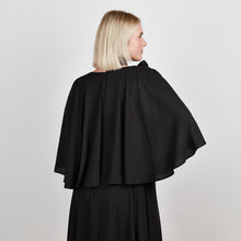 Load and play video in Gallery viewer, Video of a model wearing the Femponiq Bow Tie Neck Cape Sleeve Maxi Dress in Black, highlighting its flowing silhouette and elegant bow tie neckline.