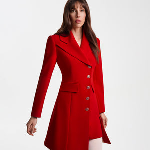 Angled front view of the Femponiq Asymmetric Pleated Blazer Dress in red, featuring a wide peak collar, padded shoulders, flap pocket, and asymmetric double-breasted line. The queen-motif buttons and tailored A-line construction emphasize the dress’s refined, structured silhouette.