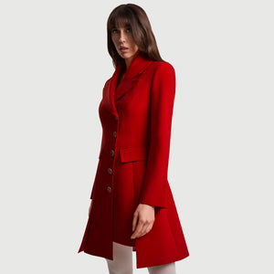 Side view of the Femponiq Asymmetric Pleated Blazer Dress in red, showing the wide peak collar, asymmetric button line, flap pocket and tailored A-line shape. The queen-motif buttons and precise paneling highlight the structured, elegant silhouette.