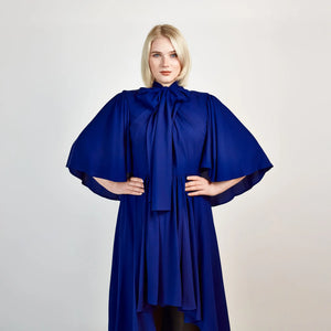 Close-up front view of the Femponiq Bow Tie Neck Cape Sleeve Maxi Dress in Royal Blue, showcasing its elegant bow tie neckline, flowing cape sleeves, and floor-length silhouette.

