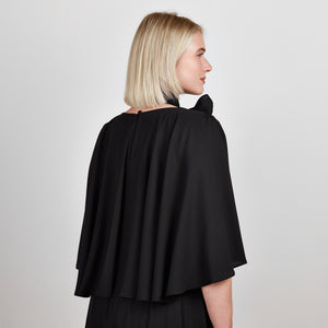 Close up view of the Femponiq Bow Tie Neck Cape Sleeve Maxi Dress in Black showcasing its elegant bow tie neckline, flowing cape sleeves, and floor-length silhouette.