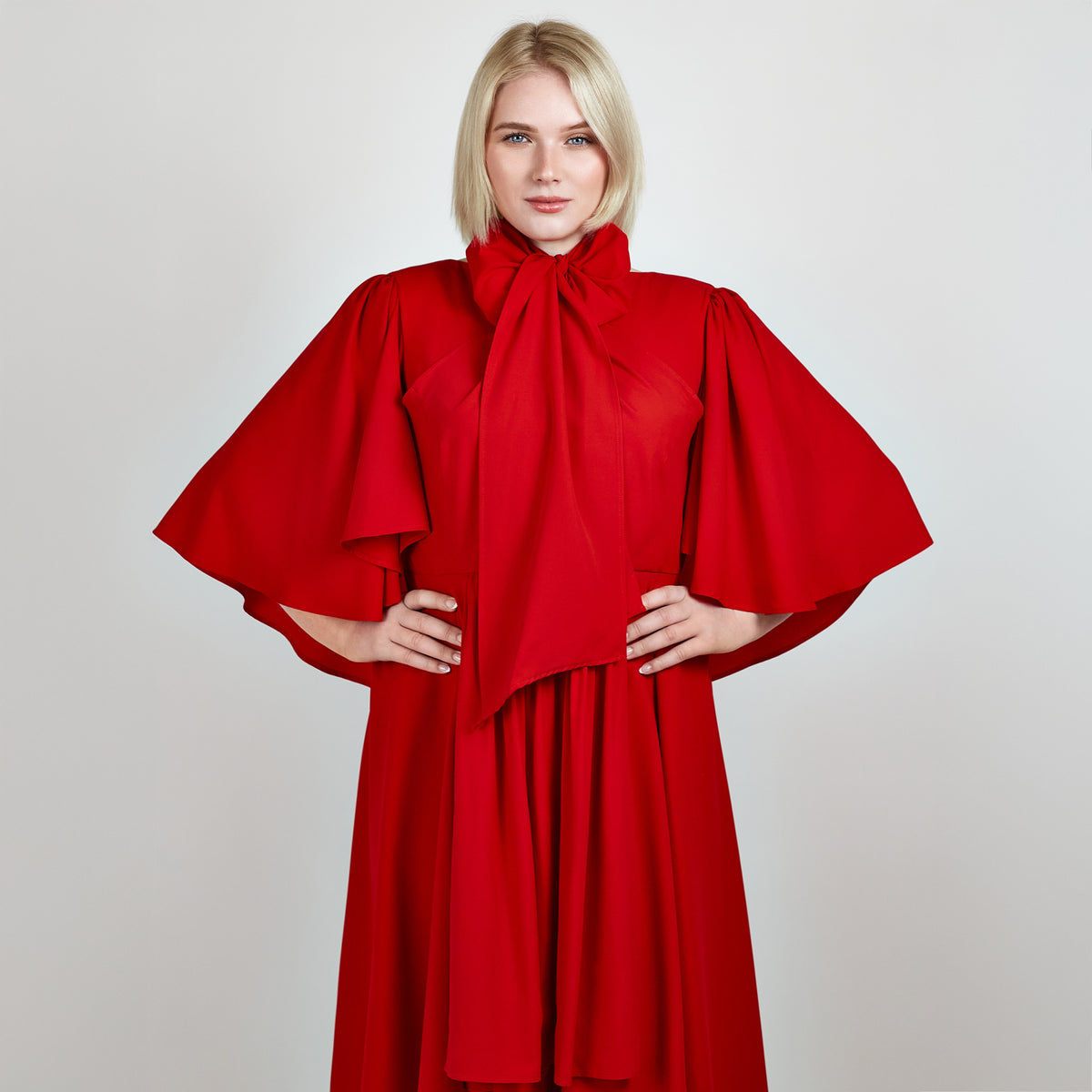 Model in a red bow-style maxi dress posing with hands on hips