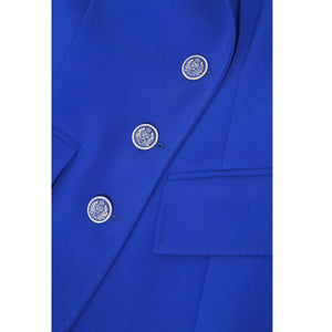 Close-up of silver button detailing on royal blue asymmetric double-breasted blazer