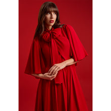 Load image into Gallery viewer, Close-up of the Femponiq Red Bow Tie Neck Cape Maxi Dress showing the oversized bow detail, flowing cape sleeves and soft draping in a monochromatic red setting.
