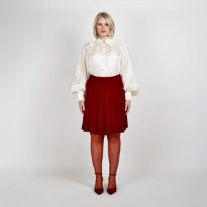Front view of Femponiq's High Waisted Pleated Skirt in wine red, highlighting its structured pleats and high waist that create a flattering silhouette above the knee.
