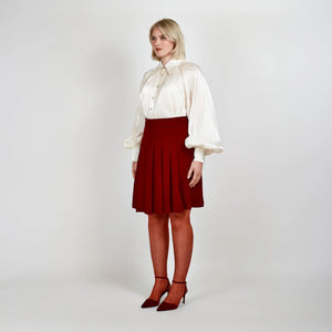 Side view of Femponiq's High Waisted Pleated Skirt in wine red, highlighting its structured pleats and high waist that create a flattering silhouette above the knee.