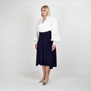 Side view of the Femponiq High-Waisted Pleated Midi Skirt with Asymmetric Dual Side Slits in Navy, featuring an elegant pleated design and asymmetric silhouette.
