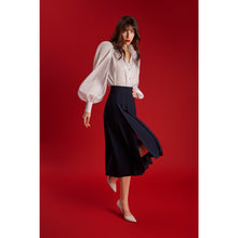 Load image into Gallery viewer, Model wearing the Femponiq High-Waisted Pleated Midi Skirt with asymmetric slits in navy, showcasing the flowing movement of the front panels while walking.
