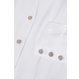 Close up view of the Femponiq Puff  Sleeve V Neck Gathered Shirt in White, showcasing its elegant and sparkly metal buttons.