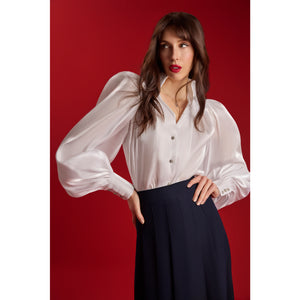 Model wearing the Femponiq Puff Sleeve V-Neck Gathered Shirt in sheer white with sparkling metal buttons, featuring voluminous puff shoulders and gathered sleeves, shown against a red background.