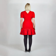 Load image into Gallery viewer, Back view of model in Femponiq Red Pleated Shoulder Peplum Hem Cady Dress, emphasizing the structured fit and elegant V neck closure at the back.
