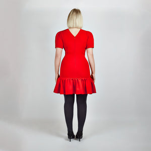 Back view of model in Femponiq Red Pleated Shoulder Peplum Hem Cady Dress, emphasizing the structured fit and elegant V neck closure at the back.