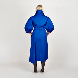 Back view of Femponiq’s Wide Lapel Asymmetric Belted Midi Cotton Dress in a vibrant blue hue, showcasing the stylish wide lapels, asymmetrical hemline, side slit pockets and flattering belt that accentuates the waist.
