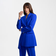 Load image into Gallery viewer, Close-up view of the model wearing the Femponiq Asymmetric Pleated Blazer in Blue, featuring a tailored fit, asymmetric design, and a bold, elegant silhouette.
