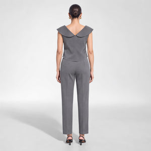 Back view of a model wearing Femponiq’s grey cupro crop top with a wide folded V-back collar and elongated curved back hem, paired with matching tailored trousers.