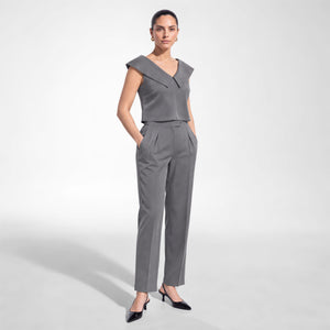 Model wearing Femponiq’s grey cupro crop top with a wide folded off-shoulder collar and flared hem, paired with matching high-waisted pleated trousers, three-quarter view.