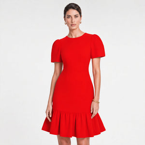 Woman wearing a bold red fitted midi dress with structured puff sleeves, a cinched waist, and a flared ruffle hem. Styled with gold pointed heels and minimal gold jewelry against a light gray background. Elegant feminine silhouette by Femponiq.