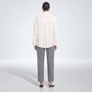 A model shown from the back wearing Femponiq's ivory long-sleeve tailored shirt and grey trousers, standing against a light gray studio background.
