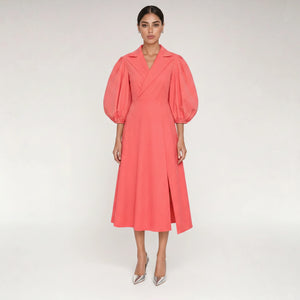Woman wearing Femponiq's
Wide Lapel Asymmetric Cotton Dress in coral pink dress with puff sleeves on a light grey background 