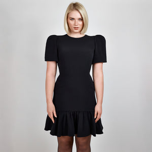 Video clip of model walking in Femponiq Black Pleated Shoulder Peplum Hem Cady Dress, showcasing its fluid movement and sophisticated design.