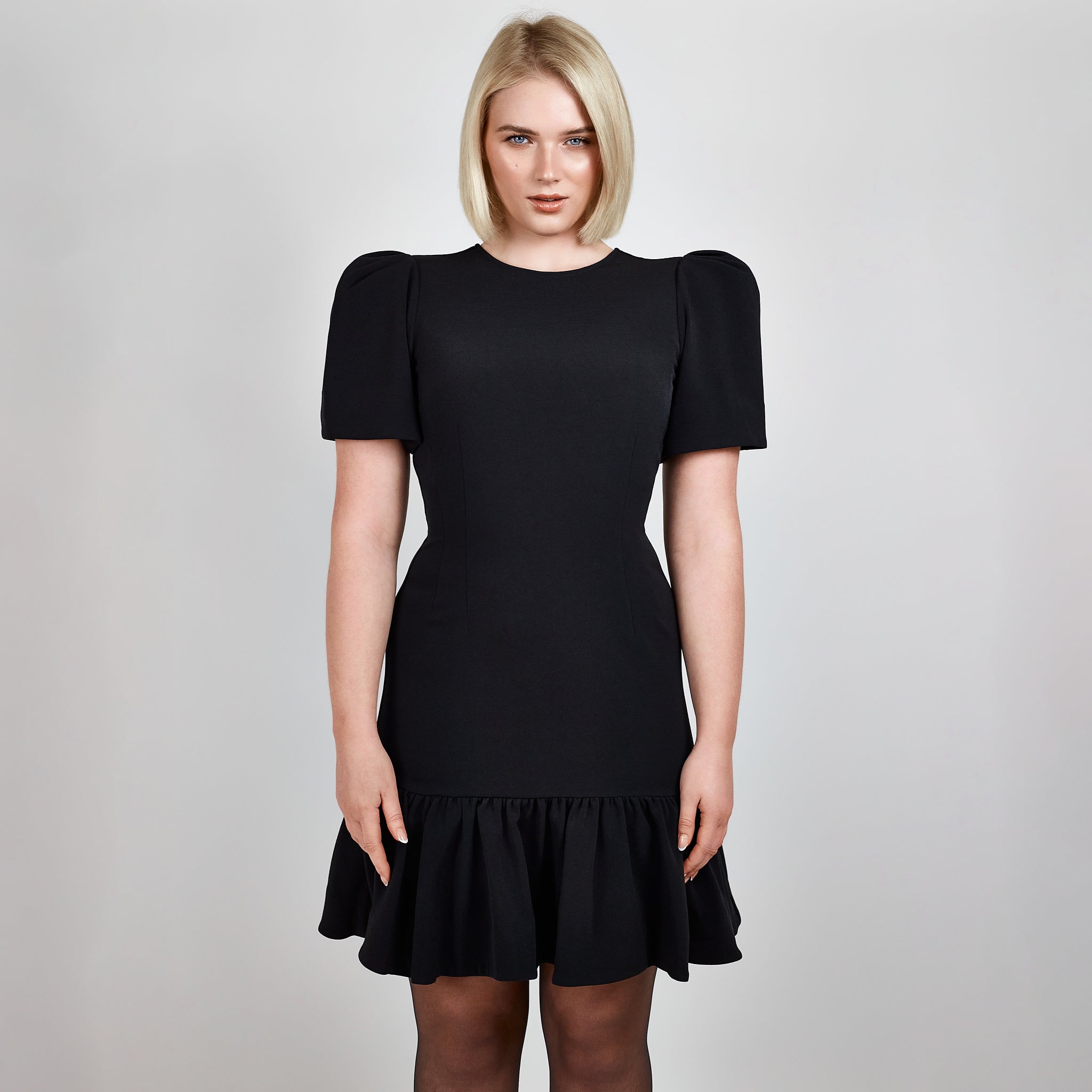 Video clip of model walking in Femponiq Black Pleated Shoulder Peplum Hem Cady Dress, showcasing its fluid movement and sophisticated design.